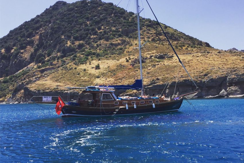 Bodrum Bitez koylarında demirlemiş ahşap kiralık özel tekne ve güneşlenen misafirler.