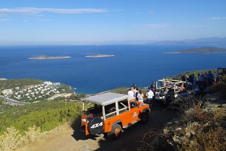 Bodrum Jeep Safari rotasında, arkasında eşsiz Ege Denizi ve adalar manzarasıyla dağlık toprak yoldan aşağı doğru ilerleyen üstü açık off-road araçları.