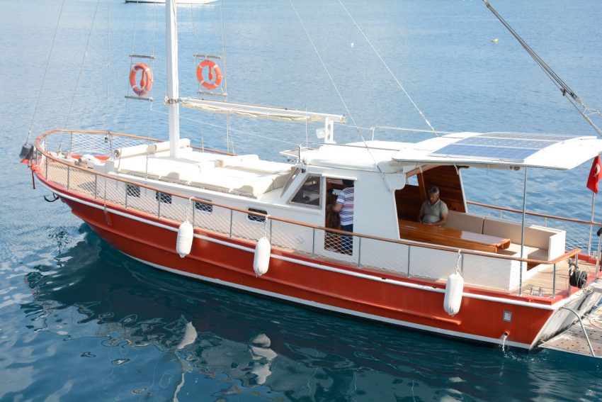 Geniş aileler ve arkadaş grupları için Bodrum özel tekne turu konforu sunan Mega Gümbet teknesinin iskelede demirliyken çekilmiş bembeyaz güneşlenme alanı manzarası.